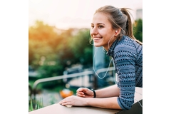 Image A women smiles while leaning over a banister on a balcony.